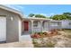 Home front entrance featuring a red door, gray stucco exterior and white accents at 7411 Seashore Dr, Port Richey, FL 34668