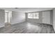 Open living room featuring gray walls, gray wood floors, a large window, and a white front door at 7411 Seashore Dr, Port Richey, FL 34668