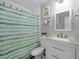Well-lit bathroom featuring a white vanity with a speckled countertop and a shower with a stylish striped curtain at 7741 Forest Trl # 6, Port Richey, FL 34668