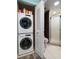 Tiled bathroom with stacked washer and dryer, toilet, and glass-enclosed shower at 7932 Sailboat Key S Blvd # 506, South Pasadena, FL 33707