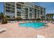 Exterior shot of the building and blue pool deck surrounded by brick and lawn chairs at 7932 Sailboat Key S Blvd # 506, South Pasadena, FL 33707