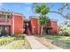 Exterior view of red brick apartment building with mature landscaping and outdoor staircases at 8220 12Th N Way # G, St Petersburg, FL 33702