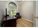 Office room featuring hardwood floors, a large window, and a black desk with a comfortable chair at 8444 Shenandoah Run, Wesley Chapel, FL 33544