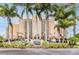 Exterior of the luxury residence featuring a manicured lawn and towering palm trees framing the building's sign at 880 Mandalay Ave # C1103, Clearwater Beach, FL 33767