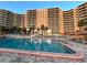 Large pool with palm trees and a multi-story condominium complex in the background on a sunny day at 880 Mandalay Ave # C1103, Clearwater Beach, FL 33767