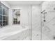 Bright bathroom featuring a soaking tub, glass-enclosed shower, and marble countertops with a window view at 9402 Woodbay Dr, Tampa, FL 33626