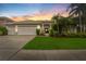 Charming single-story home featuring a three-car garage, well-manicured lawn, and lush tropical landscaping at 9402 Woodbay Dr, Tampa, FL 33626