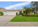 Charming single-story home featuring a three-car garage, well-manicured lawn, and lush tropical landscaping at 9402 Woodbay Dr, Tampa, FL 33626