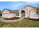 Charming one-story home featuring an arched entryway, a two-car garage, and beautifully landscaped front yard at 12214 Buckingham Way, Spring Hill, FL 34609