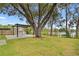 Large backyard with a dining area under a wooden pergola next to a tree and lake at 12529 Mondragon Dr, Tampa, FL 33625