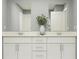 Bathroom with double vanity, white cabinetry, modern fixtures and framed mirrors at 13510 White Gold Run, Parrish, FL 34219