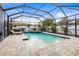 Stunning screened pool area with lounge chairs, a spa, and lush tropical landscaping at 1741 Beaconsfield Dr, Wesley Chapel, FL 33543