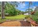 Landscaped backyard with mature trees, lush greenery, and a white fence providing privacy and charm at 1808 Sawhorse Ct, Lutz, FL 33559