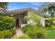 Well-maintained home exterior features an established landscape with a mature shade tree and partial front porch view at 2035 Nolan Dr, Dunedin, FL 34698