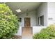 View of the front porch, walkway, and the wood paneled front door, plus an exterior light and landscaping at 2035 Nolan Dr, Dunedin, FL 34698