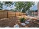 Fenced backyard with mulch, stepping stones, and a glimpse of the screened pool at 2063 Ridgecrest Dr, Dunedin, FL 34698