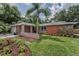 Single-story home showcasing stone accents, a side-entry garage, and a meticulously maintained front lawn at 2063 Ridgecrest Dr, Dunedin, FL 34698