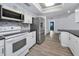 Modern kitchen with white cabinetry, stainless steel appliances, and a view to the adjacent living spaces at 2063 Ridgecrest Dr, Dunedin, FL 34698