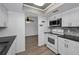A kitchen with white cabinetry, modern appliances, tile backsplash, and a view to the dining and living areas at 2063 Ridgecrest Dr, Dunedin, FL 34698