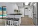 An updated kitchen with white cabinetry, black countertop, tile backsplash, stainless steel appliances, and bar seating at 2063 Ridgecrest Dr, Dunedin, FL 34698