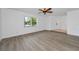 An empty living room featuring wood-look floors, ceiling fan, window, and access to the home's entryway at 2063 Ridgecrest Dr, Dunedin, FL 34698