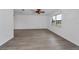 An empty living room with wood-look floors, ceiling fan, and a window showcasing the home's front yard at 2063 Ridgecrest Dr, Dunedin, FL 34698