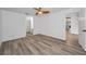 Bright main bedroom featuring a ceiling fan, wood-look floors, and a view into the ensuite bathroom at 2063 Ridgecrest Dr, Dunedin, FL 34698
