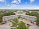 Aerial view of a three-story condominium building with balconies and parking surrounded by lush trees and beautiful blue skies at 2261 Swedish Dr # 47, Clearwater, FL 33763