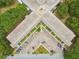 Aerial view of a three-story condominium featuring a unique V-shape design and ample parking, all surrounded by green trees at 2261 Swedish Dr # 47, Clearwater, FL 33763