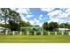 Charming single-story home with a well-manicured lawn and a stylish black fence, nestled among lush trees under a partly cloudy sky at 27752 Ravens Brook Rd, Wesley Chapel, FL 33544