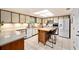 Bright kitchen featuring tile floors, white appliances, and a center island with seating at 39243 6Th Ave, Zephyrhills, FL 33542