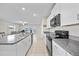 Modern kitchen with granite countertops, white cabinets, and stainless steel appliances, flowing into the living area at 4403 Eternal Prince, Sun City Center, FL 33573