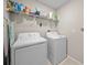 A functional laundry room with a washer, a dryer, and storage shelving at 4403 Eternal Prince, Sun City Center, FL 33573