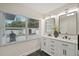 Bright bathroom featuring a double vanity, sleek mirrors, and a view through the window to the outdoors at 4609 S Lois Ave, Tampa, FL 33611