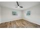 Bright bedroom featuring wood-look floors, a modern ceiling fan, and ample natural light from two windows at 4609 S Lois Ave, Tampa, FL 33611