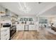 Open concept kitchen with white cabinets, stainless steel appliances, geometric backsplash, and wood-look flooring at 4609 S Lois Ave, Tampa, FL 33611