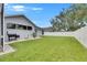 Wide shot of home's backyard with healthy green lawn, white fence and patio seating at 5117 Whispering Leaf Trl, Valrico, FL 33596