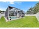 Backyard pool enclosed with a screen, surrounded by a green lawn and white fence at 5117 Whispering Leaf Trl, Valrico, FL 33596