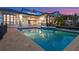 Sparkling backyard pool and spa reflect the lush landscaping and custom-built home at twilight at 5287 61St S Ave, St Petersburg, FL 33715