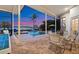 Outdoor living features covered lanai with outdoor seating, pool, spa, and waterfront views at dusk at 5287 61St S Ave, St Petersburg, FL 33715