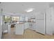 Well-lit open kitchen features white cabinets, tile floor, and a view of the living room and balcony at 5445 Gulf Blvd # 210, St Pete Beach, FL 33706