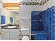 Bathroom featuring blue tiled shower and a white toilet with a sink and mirror at 625 Fayette S Dr, Safety Harbor, FL 34695