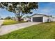 Charming single-story home with a well-manicured lawn, a dark garage door, and mature trees at 6920 13Th N Ave, St Petersburg, FL 33710