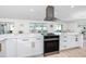 Bright, open kitchen featuring white cabinetry, quartz countertops, and stainless steel appliances and range hood at 6920 13Th N Ave, St Petersburg, FL 33710