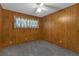 This bedroom offers wood paneling, a window with curtains, carpet, and a ceiling fan with light at 7002 Doreen St, Tampa, FL 33617