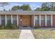 The front entrance of a brick home, featuring a wood door, plants, and sidelight windows at 7002 Doreen St, Tampa, FL 33617