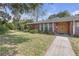 A single-story brick home with a well-manicured front lawn and a walkway at 7002 Doreen St, Tampa, FL 33617