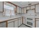 Cozy kitchen featuring white cabinets, double oven, and a window with patterned curtains at 7002 Doreen St, Tampa, FL 33617