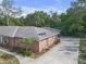 Back exterior of a brick home featuring a driveway, a well-maintained roof, and mature landscaping at 7002 Doreen St, Tampa, FL 33617