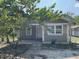Single-story home exterior with neutral paint and simple landscaping, partially shaded by a mature tree at 7806 N Orleans Ave, Tampa, FL 33604